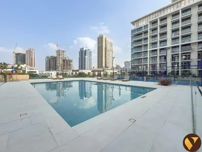 a swimming pool in front of a tall building at Vogue JVC Binghatti Phoenix near Circle Mall, Studio Apartment with Balcony and Access to all Amenities in Dubai