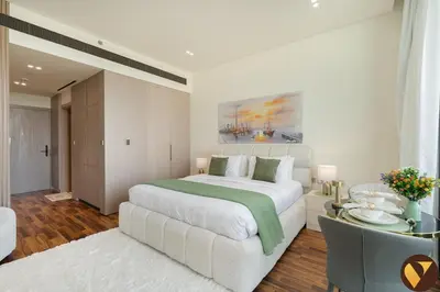 a white bedroom with a large bed and a table at Vogue JVC Binghatti Phoenix near Circle Mall, Studio Apartment with Balcony and Access to all Amenities in Dubai