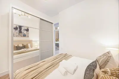 a white bedroom with a bed and a mirror at ShoresInn - Sleek & Modern Stay at Dubai Marina in Dubai