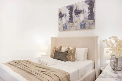 a white bedroom with a bed with pillows at ShoresInn - Sleek & Modern Stay at Dubai Marina in Dubai