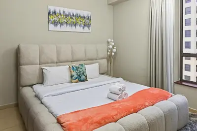 a bedroom with a large bed with an orange blanket at Luxury 2BR l High Floor l Marina View l JBR in Dubai