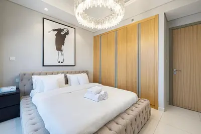 a bedroom with a large white bed with a chandelier at Luxe 3BR with Infinity Pool and Burj Khalifa View l High Floor in Dubai
