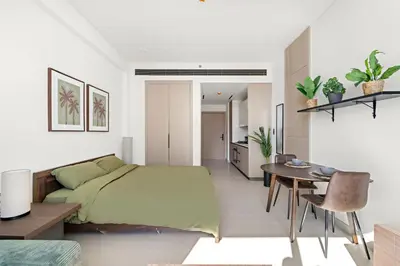 a bedroom with a bed and a table and a dining room at Modern Studio in Prime JVC Padel, Pool & Gym in Dubai