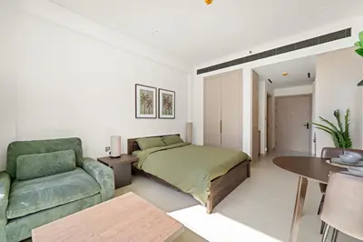a bedroom with a bed and a couch and a table at Modern Studio in Prime JVC Padel, Pool & Gym in Dubai