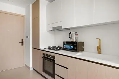 a kitchen with a stove and a sink and a microwave at Modern Studio in Prime JVC Padel, Pool & Gym in Dubai