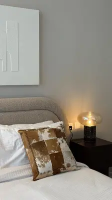 a bed with a pillow and a lamp on a table at Stunning Brand New Stylish Studio in JVC in Dubai