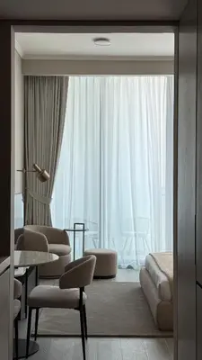 a hotel room with a large window and a table and chairs at Stunning Brand New Stylish Studio in JVC in Dubai