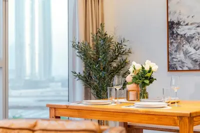 a wooden table with plates and glasses and flowers on it at DIFC 1 Bed, City View, 600m to Metro, Sleeps 4 in Dubai