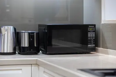a microwave sitting on a kitchen counter next to a coffee pot at Chic 1BR near Burj Khalifa - Downtown in Dubai