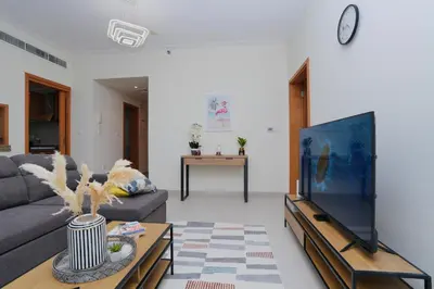 a living room with a couch and a tv at Bright 1BR Marina Promenade Partial Sea View in Dubai