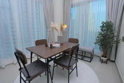 a dining room with a table and chairs and windows at Bright 1BR Marina Promenade Partial Sea View in Dubai
