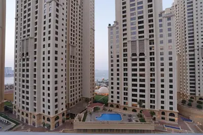 two tall buildings with a pool in between them at Bright 1BR Marina Promenade Partial Sea View in Dubai