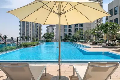 a pool with two chairs and an umbrella at Creek Harbour Home Burj Khalifa Downtown View in Dubai