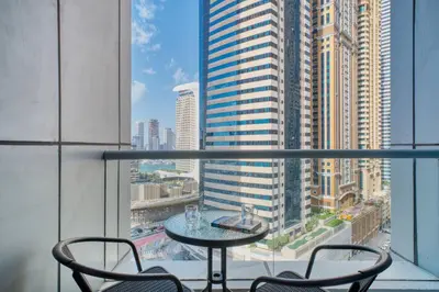 a table and chairs on a balcony with a view of a city at Stylish Large 2BR Apartment in the Heart of Dubai Marina in Dubai