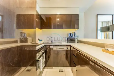 a kitchen with stainless steel appliances and wooden cabinets at Chic 2BR Apartment, Near Dubai Mall and Fountain - Damac Majestine, Business Bay by Deluxe Holiday Homes in Dubai