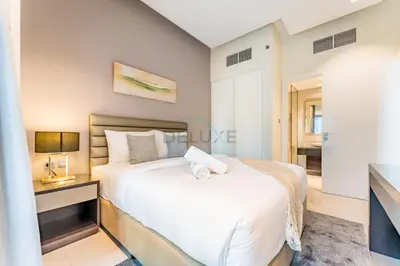 a bedroom with a large white bed and a desk at Chic 2BR Apartment, Near Dubai Mall and Fountain - Damac Majestine, Business Bay by Deluxe Holiday Homes in Dubai