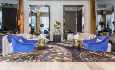a lobby of a hotel with blue chairs and tables at Chic 2BR Apartment, Near Dubai Mall and Fountain - Damac Majestine, Business Bay by Deluxe Holiday Homes in Dubai
