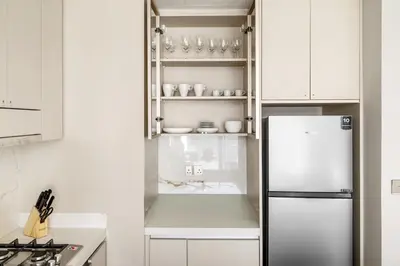 a kitchen with a refrigerator and white cabinets at Brand New 1BR Apartment In Amalia Residences Al Furjan in Dubai