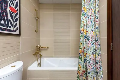 a bathroom with a tub and a shower curtain at Waves - Nature-Inspired Studio - JLT Skyline Living in Dubai