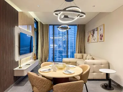 a living room with a table and chairs and a couch at Stylish & Cozy Fully Furnished 2BR plus Maid Crest C in Dubai
