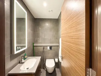 a bathroom with a white toilet and a sink at Stylish & Cozy Fully Furnished 2BR plus Maid Crest C in Dubai