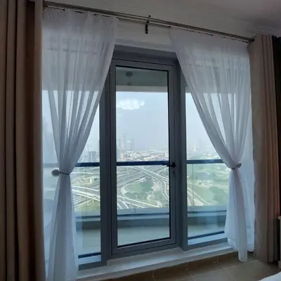 a window with white curtains and a view of a city at Modern 1BR Duplex Jumeirah Bay X1-1 In JLT in Dubai