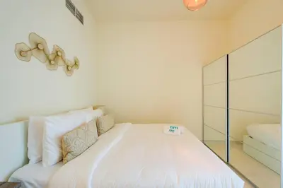 a bedroom with a white bed with a glass cabinet at Elegant 1BR in Polo Residences Nad Al Sheba in Dubai