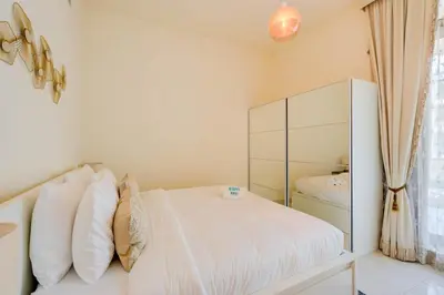 a bedroom with a white bed and a mirror at Elegant 1BR in Polo Residences Nad Al Sheba in Dubai