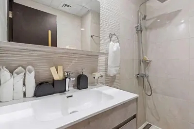 a white bathroom with a sink and a shower at Stylish Pool-View Studio w Balcony & King Bed in Dubai