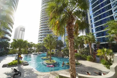 a swimming pool with palm trees and buildings at Stylish 2BR Paramount Tower D in Dubai