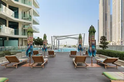 a deck with chairs and umbrellas and a pool at Stylish Missoni Studio With Direct Pool Access in Dubai