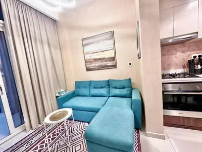a living room with a blue couch and a kitchen at 01BR apartment in DAMAC Vera Residences in Dubai