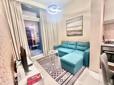 a living room with a blue couch and a tv at 01BR apartment in DAMAC Vera Residences in Dubai