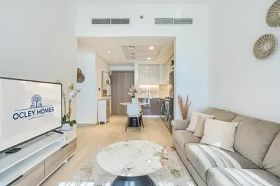 a living room with a couch and a tv at Bright & Stylish Home in the Heart of Meydan in Dubai