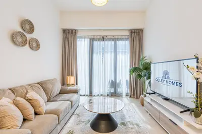 a living room with a couch and a tv at Bright & Stylish Home in the Heart of Meydan in Dubai