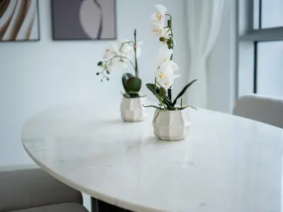 two white vases with flowers on a white table at Marina Beachfront Oasis Infinity Pool & Modern Comfort in Dubai
