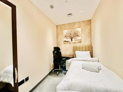 two beds in a room with a desk and a chair at Modern Fully Furnished 1BR plus Study in Crest Tower B in Dubai