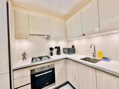 a kitchen with white cabinets and a sink at Modern Fully Furnished 1BR plus Study in Crest Tower B in Dubai