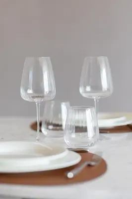 four wine glasses and plates on a table at The Opus Residences Luxury Design in Dubai