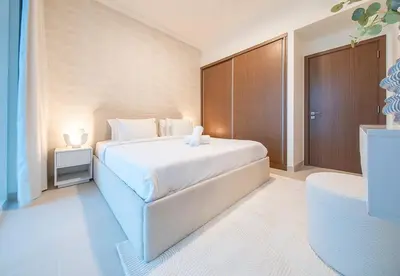 a bedroom with a white bed and a wooden cabinet at 1 Bed in Palace Beach Residence with sea view in Dubai