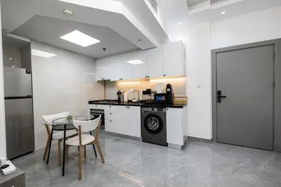 a kitchen with white cabinets and a table and a dishwasher at Dubai Marina - Comfy 1BHK Apartment in Dubai