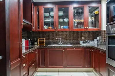 a kitchen with wooden cabinets and a sink at Werova - Spacious 1-Bedroom Apartment for Rent in Dubai