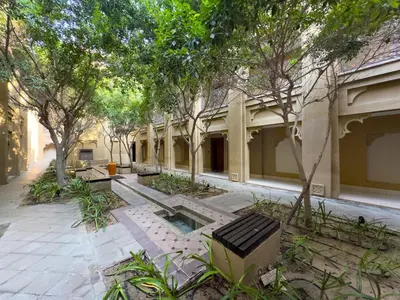 a building with two benches in a courtyard with trees at Werova - Spacious 1-Bedroom Apartment for Rent in Dubai