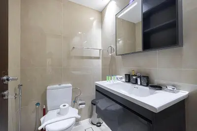 a bathroom with a toilet and a sink and a mirror at Stylish Silicon Oasis Studio Near Mall & Airport in Dubai
