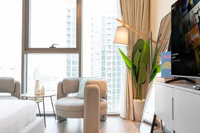 a living room with a tv and a couch and a chair at Livin' Holidays -Studio - Azizi Magnificent Studio in Dubai