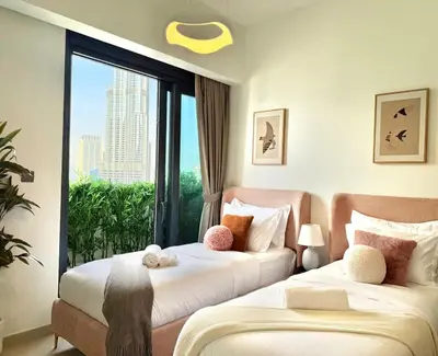 two beds in a room with a large window at SKYLiNE - 4 BR - BURJ KHALiFA & FOUNTAiN ViEW in Dubai
