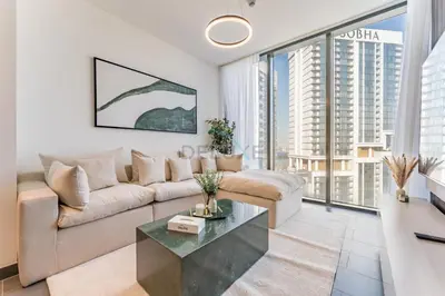 a living room with a couch and a table at Prime 1BR, Few minutes Drive to Burj Khalifa and Dubai Mall - Sobha Hartland The Crest Tower C by Deluxe Holiday Homes in Dubai