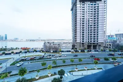 a parking lot in a city with a large building at 1BR Lake & Harbour View Dubai Creek Harbour in Dubai