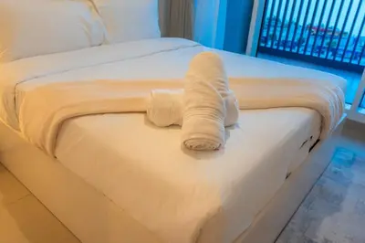 a white towel is sitting on a bed at 1BR Lake & Harbour View Dubai Creek Harbour in Dubai