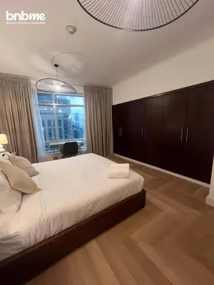 a bedroom with a large white bed and a table at bnbmehomes - Burj Views East Tower in Dubai